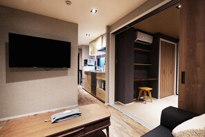 Uma sala de estar moderna com uma TV de tela plana, uma mesa de centro de madeira e um sofá.