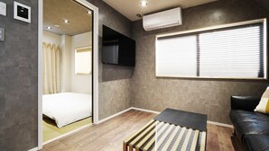 Una habitación moderna con cama, televisión, aire acondicionado y ventana con persianas.