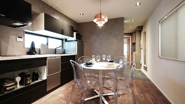 Una cocina moderna con zona de comedor, con una mesa redonda y sillas, horno empotrado y una lámpara colgante.