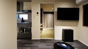 A modern hotel room with a kitchen area, a television mounted on the wall, and a small trash bin. - Real Life SANGENJAYA 1BR  2Pax Shibuya (Meguro)