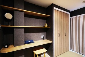Simple, functional space with storage, a wardrobe, and a window with sheer curtains.