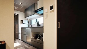 A modern kitchen with built-in appliances, a microwave, and a coffee maker on the countertop. - Real Life SANGENJAYA 1BR  2Pax Shibuya (Meguro)