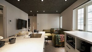 A compact living space with a kitchenette, a dining area, and a seating area with a sofa and a TV. - Real Life AOYAMA 2BR suite 5pax 3bed 3min metro (Minato)
