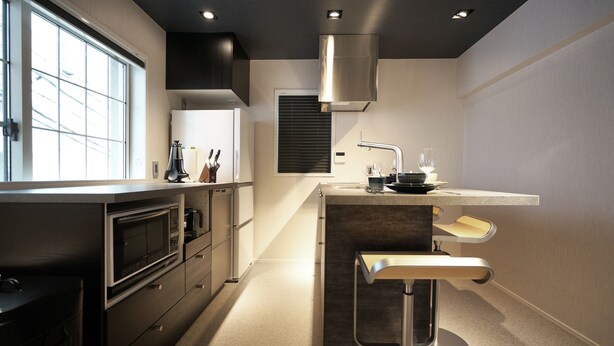 Een moderne keuken met een inbouwoven, een magnetron, een roestvrijstalen afzuigkap en een bar met krukken.