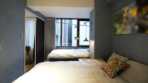 A modern hotel room with a large bed, a window with curtains, and a view of the city.