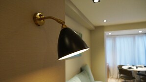 A modern room with a wall-mounted lamp, a dining area with a round table and chairs, and a light blue sofa.