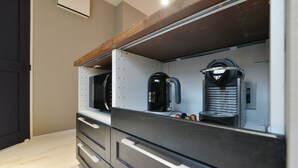 A modern kitchen with built-in appliances, including a coffee maker and a kettle, and a wooden countertop.