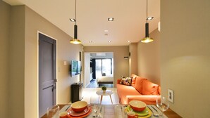 A modern hotel room with a dining area, a sofa, and a television.