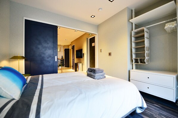 A modern hotel room with a large bed, a walk-in closet, and a bathroom visible through an open door. - Real Life Meguro River Fancy 1BR 4Pax Shibuya (Setagaya)