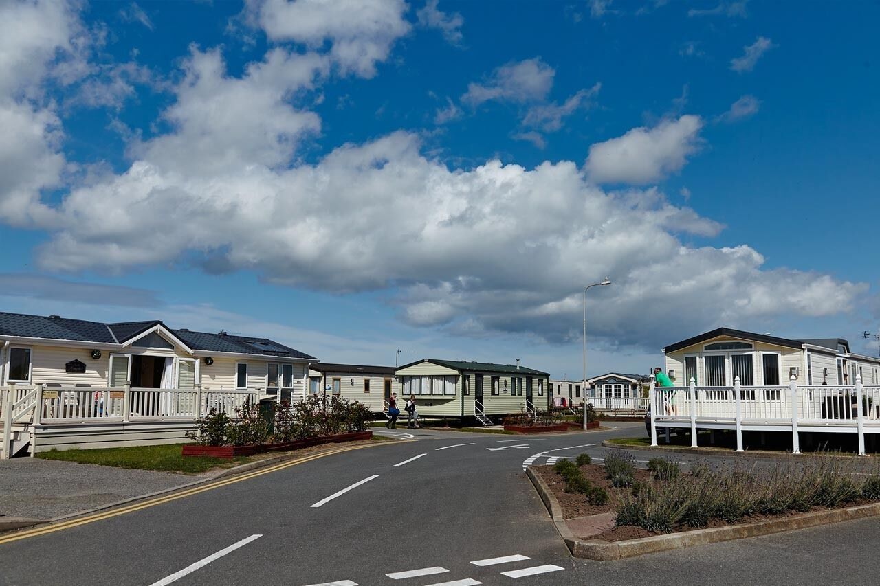 A row of mobile homes with a paved road in front.