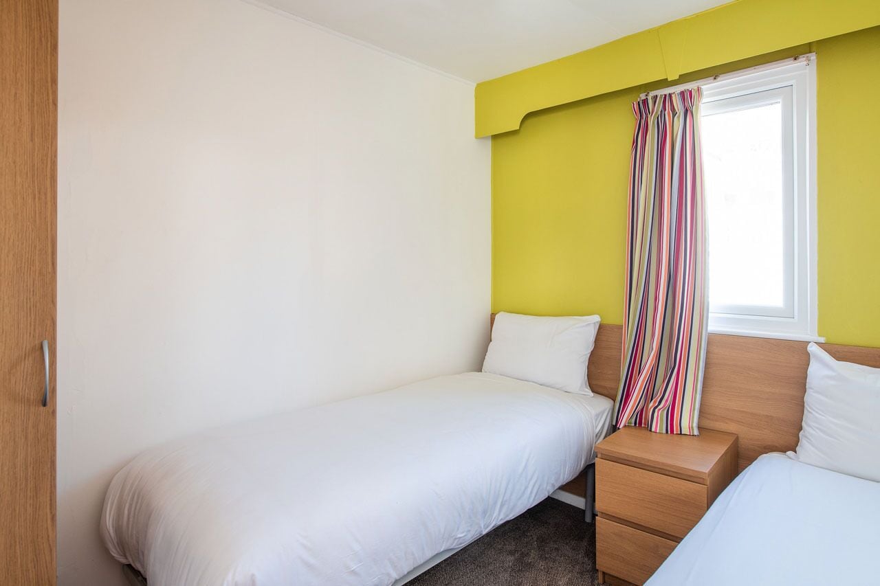 A single bed with a wooden headboard and a nightstand with a drawer.