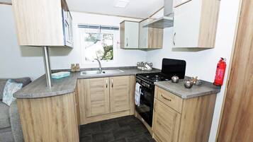 A compact kitchen with wooden cabinets, a black stove, and a window.