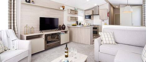 A modern living room with a flat-screen TV, a coffee table with a magazine, and a sofa.