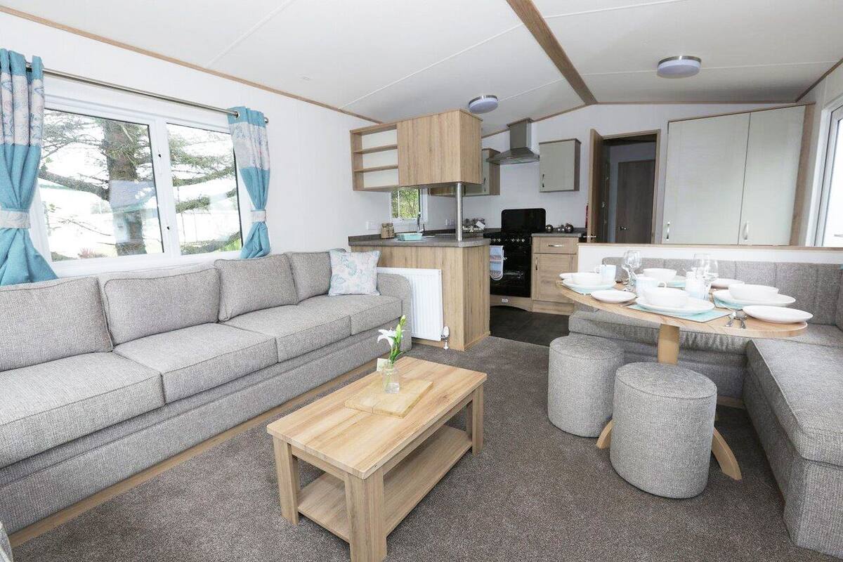 Un espacio habitable compacto con un sofá, una mesa de centro de madera y una zona de comedor con taburetes.