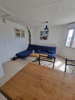 A living room with a blue sofa, a wooden coffee table, and a ceiling fan.