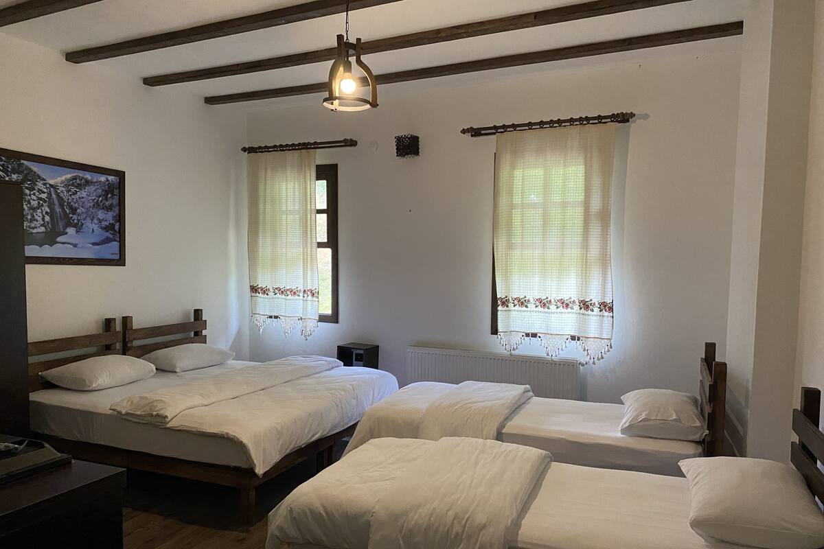 Une chambre avec deux lits, des têtes de lit en bois, une petite table et un luminaire suspendu.