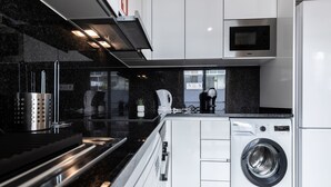 Een moderne keuken met een ingebouwde wasmachine, roestvrijstalen apparatuur en een zwart aanrecht.