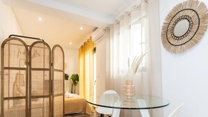 Een moderne slaapkamer met een glazen tafel, witte stoelen en een bed met hoofdbord.
