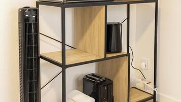 Una kitchenette compacta con microondas, tostadora y cafetera sobre un soporte de metal negro.