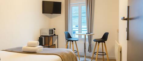 Une chambre d’hôtel équipée d’un lit, d’une télévision, d’un four à micro-ondes, de deux chaises et d’une petite table.