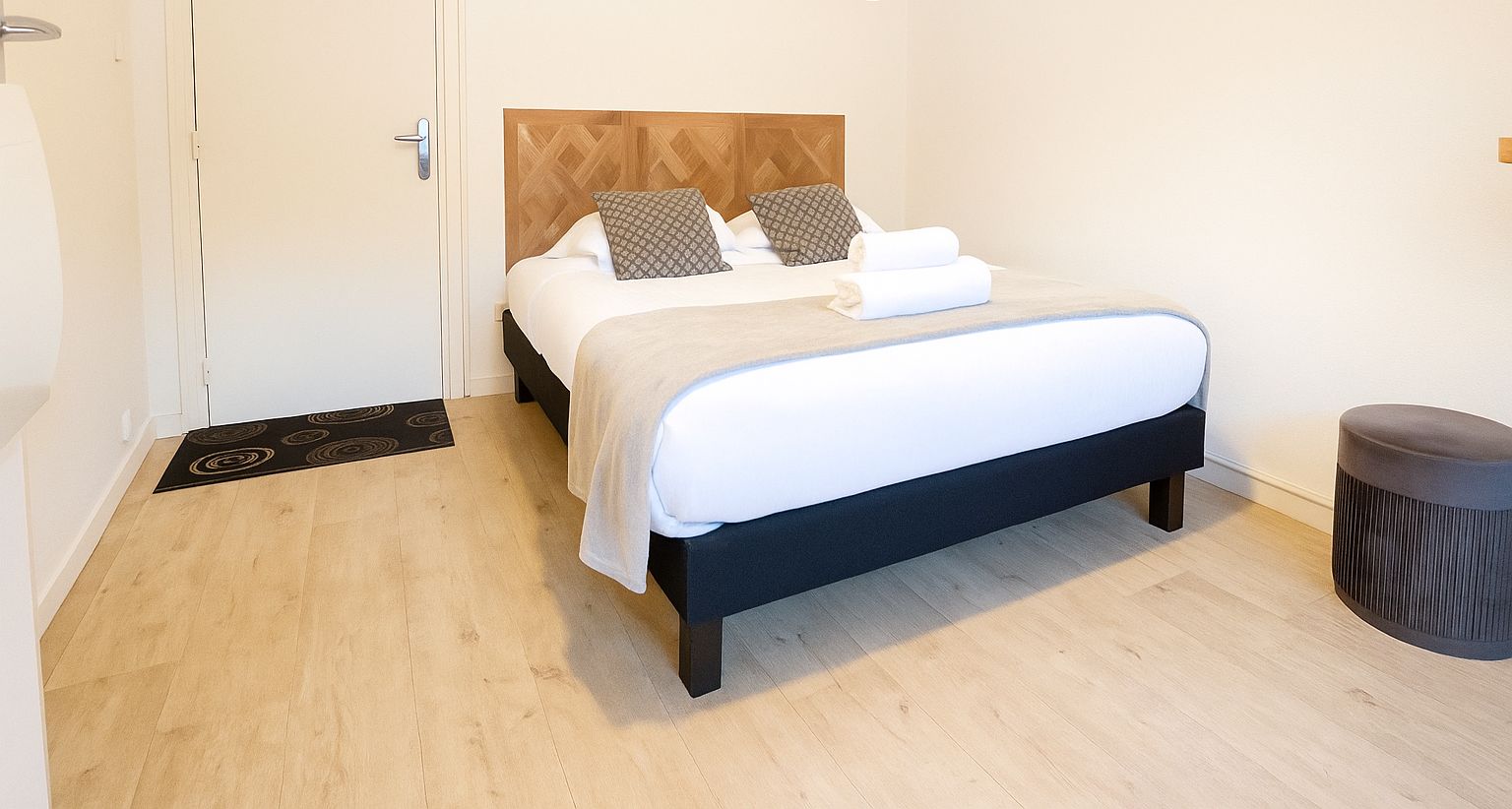 Et hotelværelse med seng, sengebord, stol og dør.