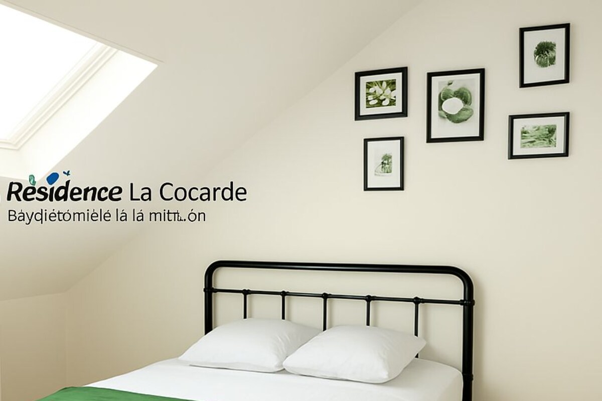 A single bed with a black metal frame, white bedding, and a green throw blanket. There are framed pictures on the wall above the bed.
