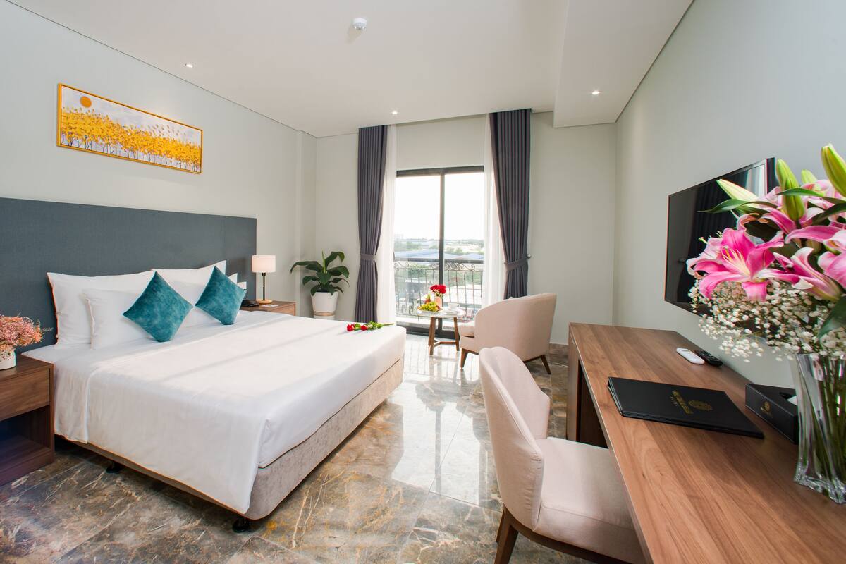 Een hotelkamer met een groot bed, een bureau, een televisie en een balkon met uitzicht.