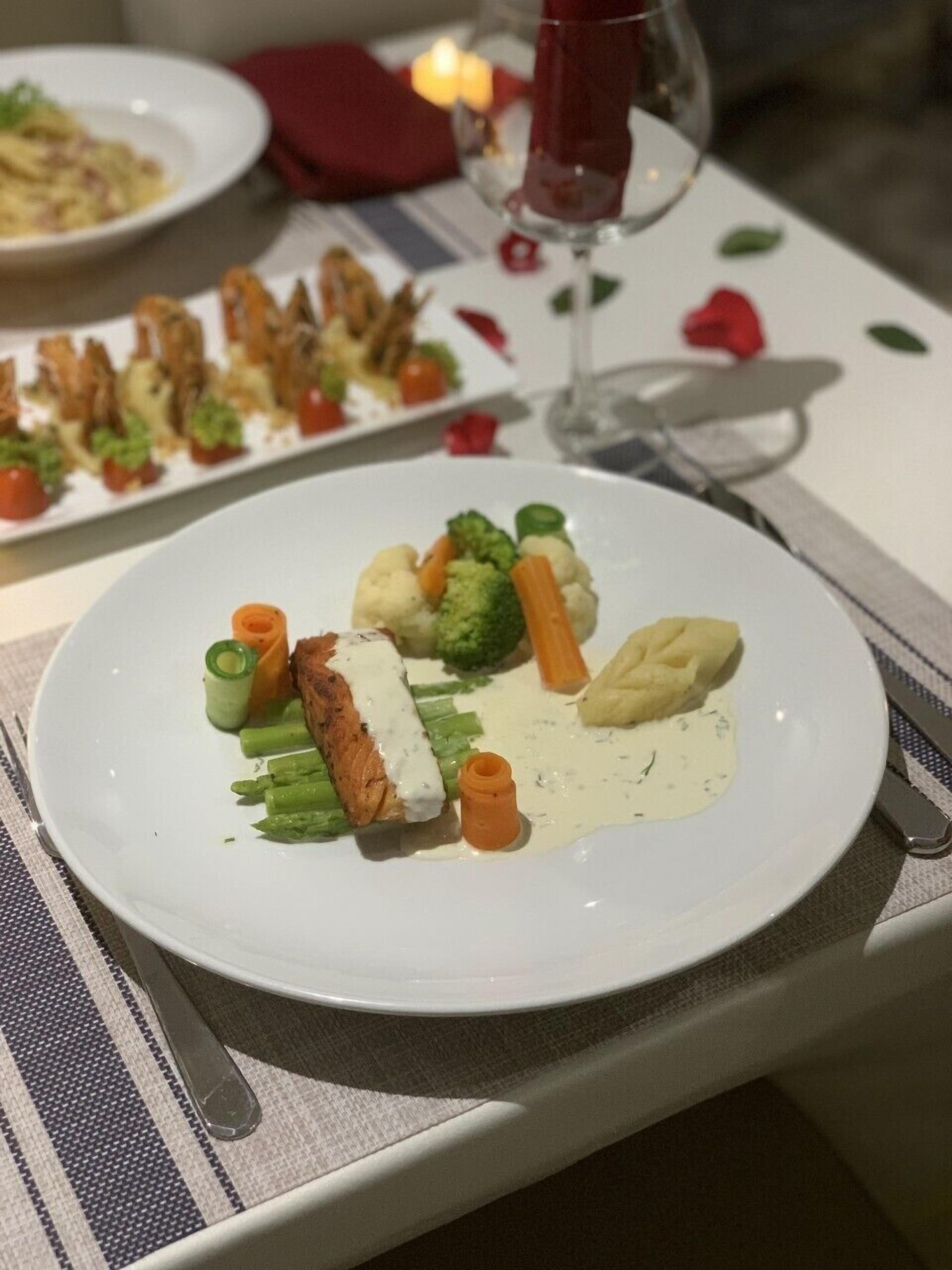 Una mesa de comedor con platos de comida, una copa de vino y cubiertos.