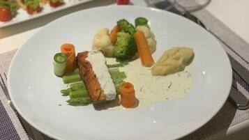 Una mesa de comedor con platos de comida, una copa de vino y cubiertos.
