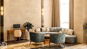 A modern living room with a sectional sofa, two armchairs, a desk with a computer, and a potted plant. - Phu Thang Grand Hotel (Duc Hoa)