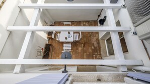 A rooftop terrace with a white railing, a small table with chairs, and a potted plant. - Pimpotta House (Ravenna)