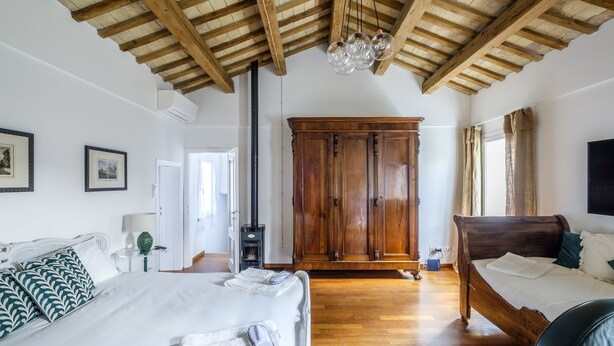 A bedroom with a wooden ceiling, a large wardrobe, a bed with white bedding, and a bedside table. - Pimpotta House (Ravenna)