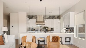 A modern kitchen with white cabinets, a marble backsplash, and pendant lighting. - Breathtaking Wildfire Golf Views | Pool (Phoenix)