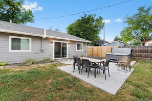 A backyard with a patio, a grill, and a wooden fence. - East Side Oasis with Hot Tub (Loveland)