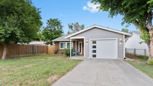 A single-story house with a garage, a front yard, and a wooden fence. - East Side Oasis with Hot Tub (Loveland)