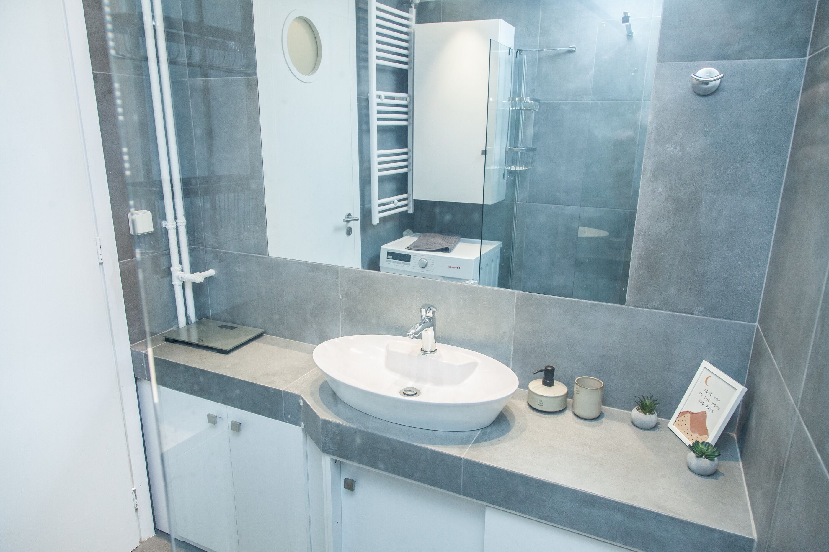 A modern bathroom with a round sink, a glass shower enclosure, and a towel rack.