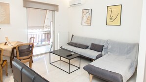 A modern living room with a grey sofa, a coffee table, and a dining area with wooden chairs and a table. - Gorgeous apartment in Central Athens (Athens)