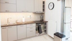 A modern kitchen with light-colored cabinets, a stainless steel oven, a sink, and a clock on the wall. - Gorgeous apartment in Central Athens (Athens)