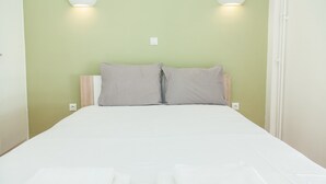 A bed with white bedding and two pillows, a light green wall, and two wall-mounted light fixtures. - Gorgeous apartment in Central Athens (Athens)