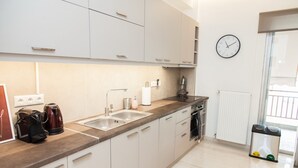 A modern kitchen with white cabinets, a double sink, a coffee maker, and a clock on the wall. - Gorgeous apartment in Central Athens (Athens)