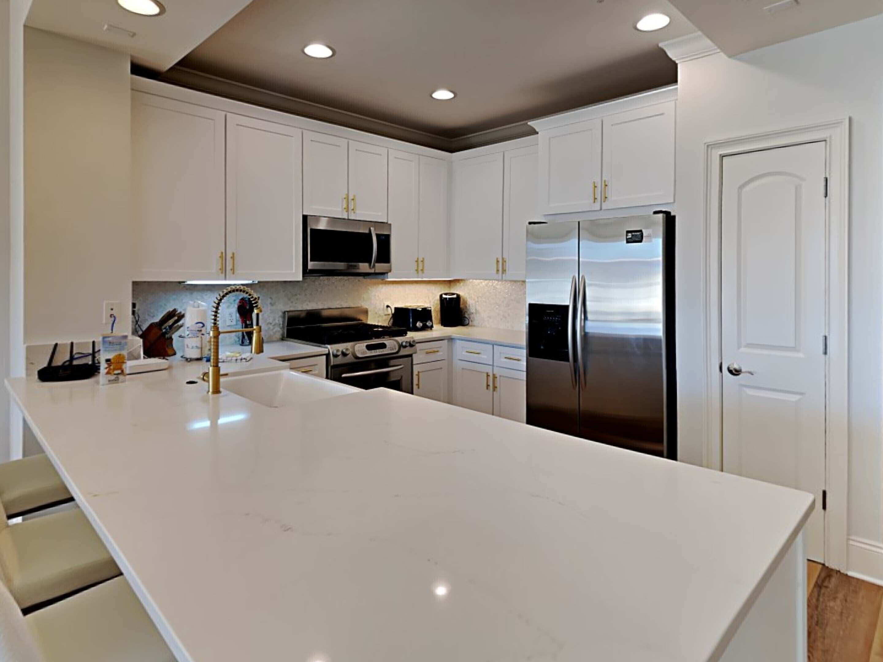 Una cocina moderna con armarios blancos, electrodomésticos de acero inoxidable y una isla grande.