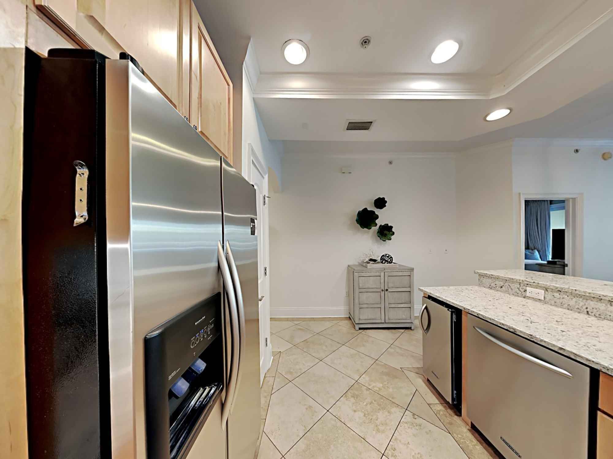 A modern kitchen with stainless steel appliances, a grey cabinet, and a marble countertop.