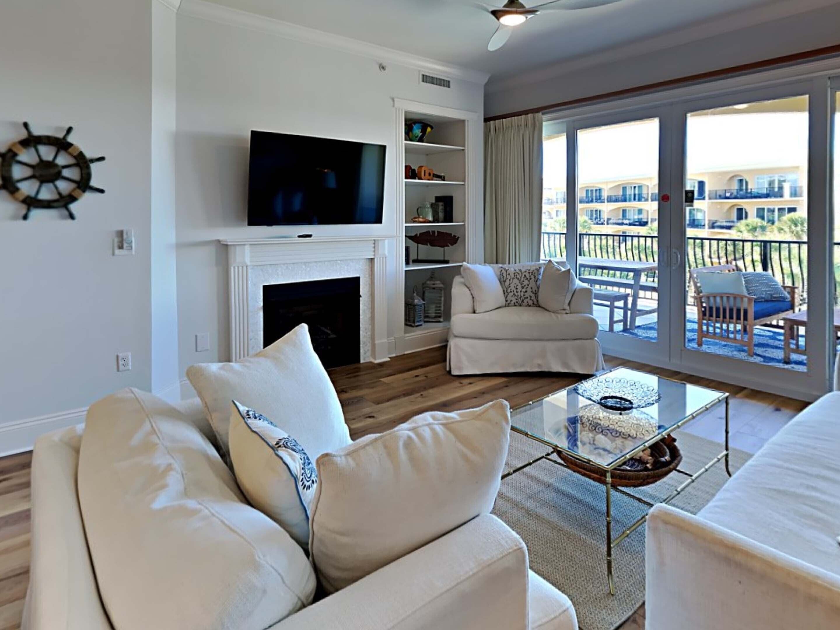 A living room with a fireplace, a television, and a balcony with outdoor furniture.