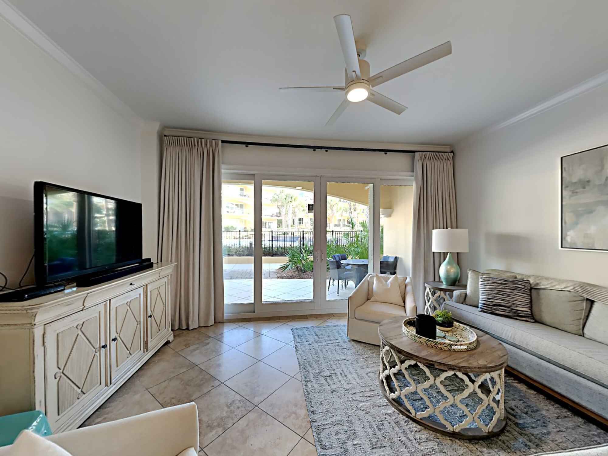 A living room with a television, sofa, coffee table, and a ceiling fan.