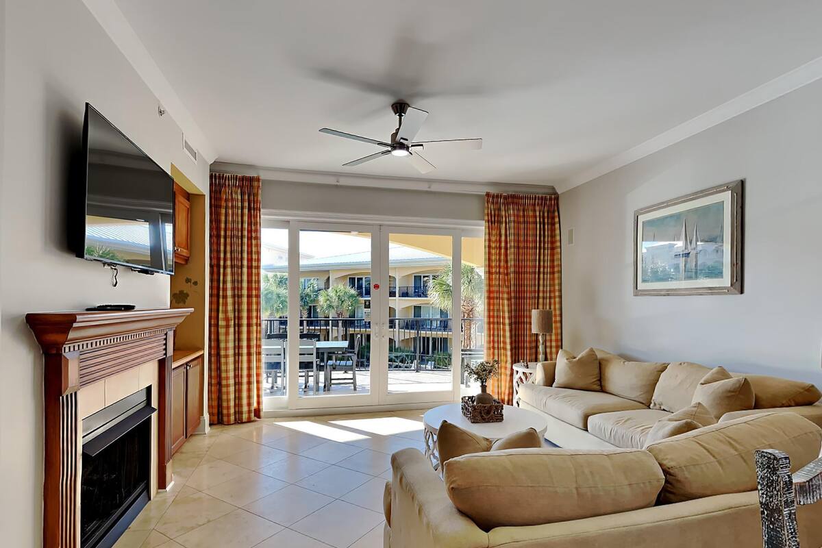 A living room with a fireplace, a sofa, a television, and a ceiling fan.