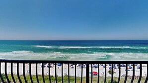A beach view with a railing, ocean waves, and beach umbrellas. - Adagio by Southern Vacation Rentals (Santa Rosa Beach)