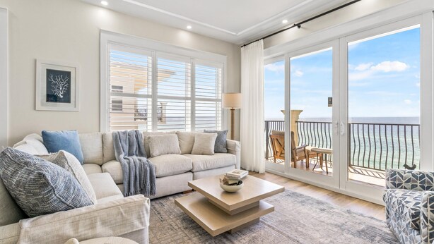 A spacious living room with a large window, a sofa, a coffee table, and a view of the ocean. - Adagio by Southern Vacation Rentals (Santa Rosa Beach)