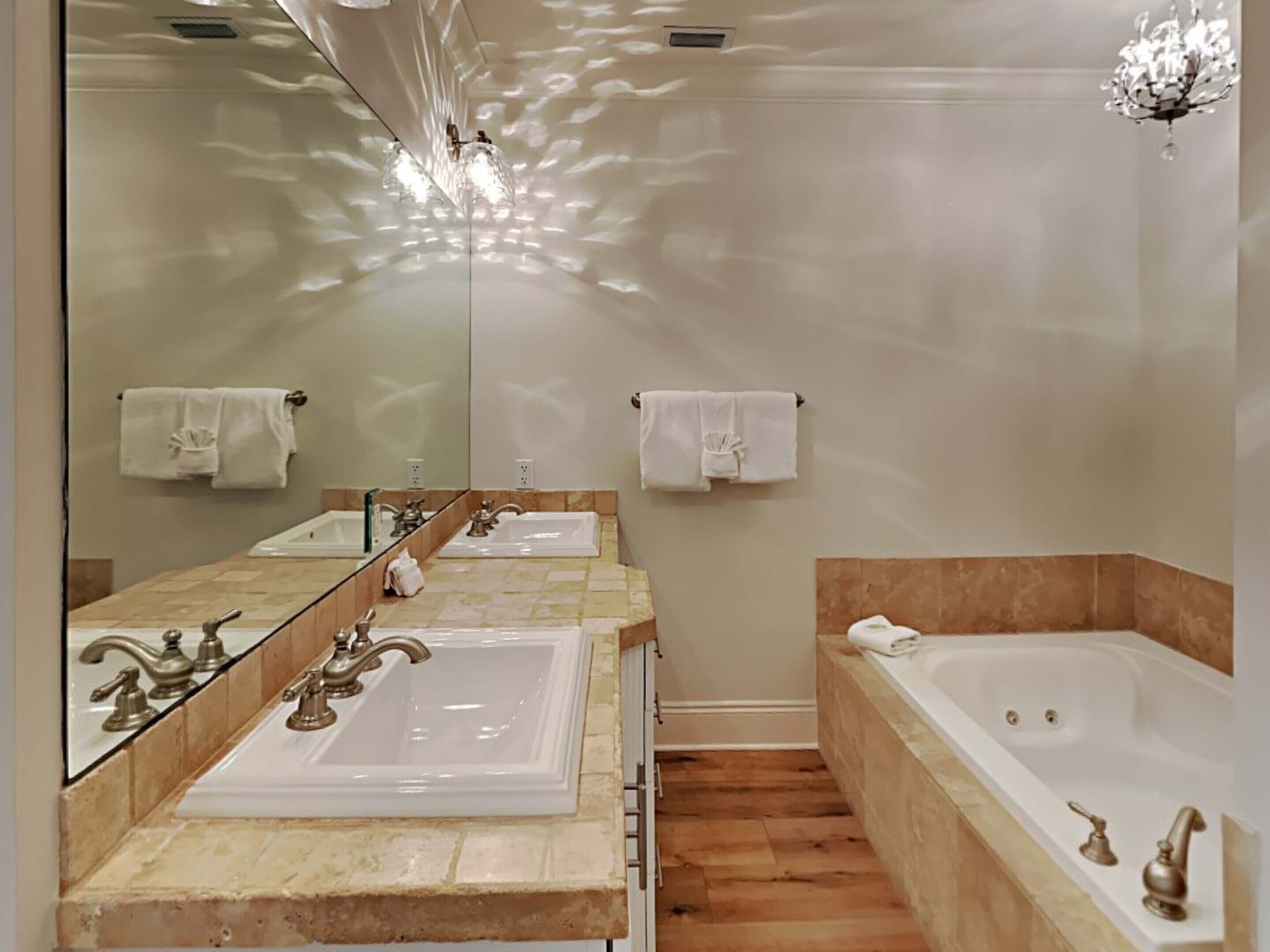 Een moderne badkamer met twee wastafels, een groot bad en een spiegel die de ruimte weerspiegelt.