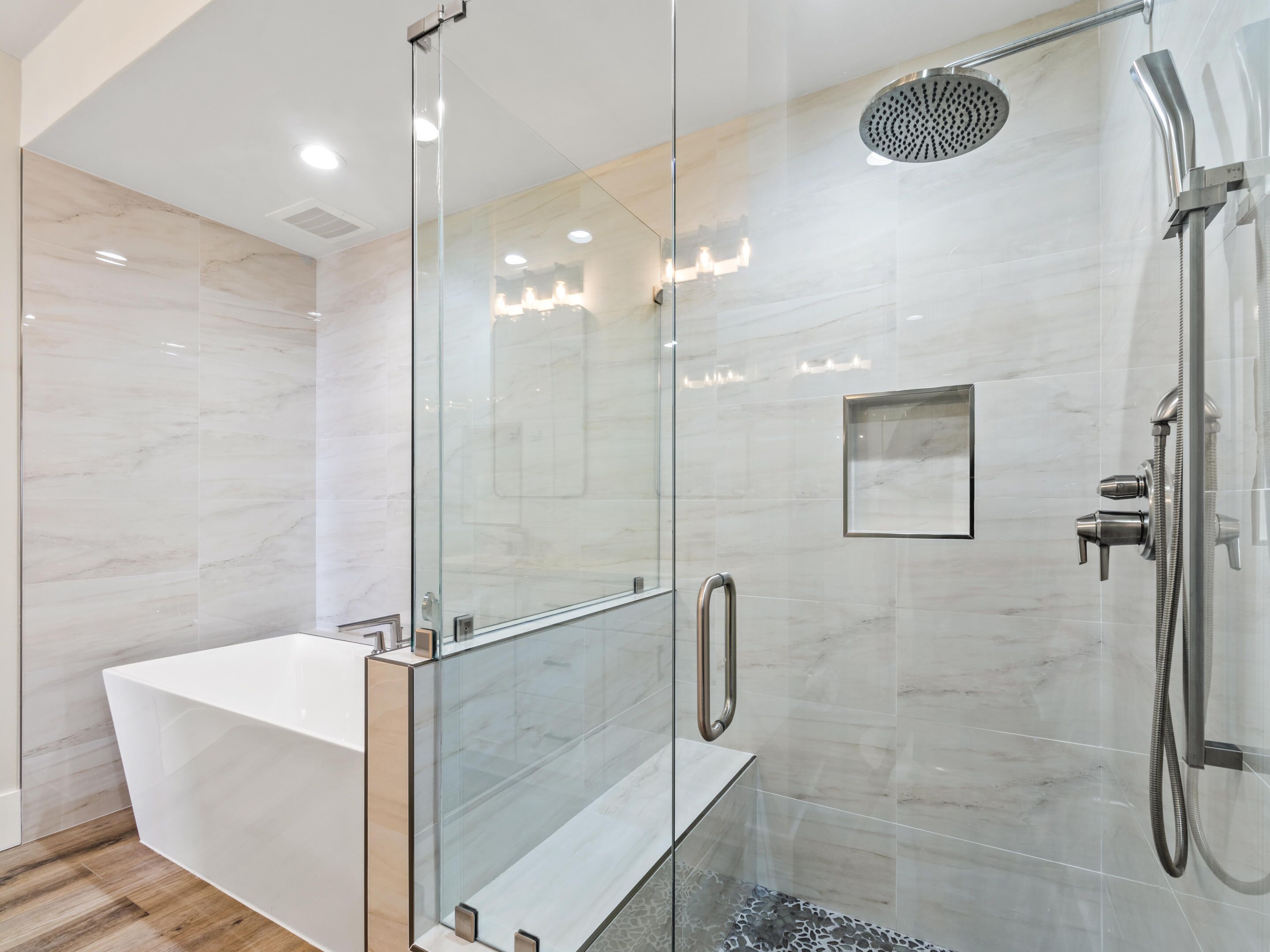 A modern bathroom with a glass-enclosed shower, a freestanding bathtub, and a glass shower door.