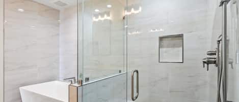 A modern bathroom with a glass-enclosed shower, a freestanding bathtub, and a glass shower door.